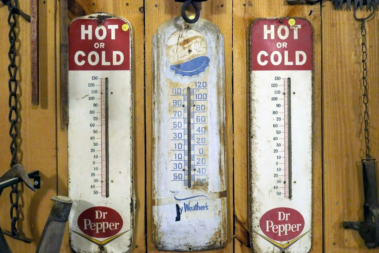 Three vintage metal thermometers mounted on a wooden wall.